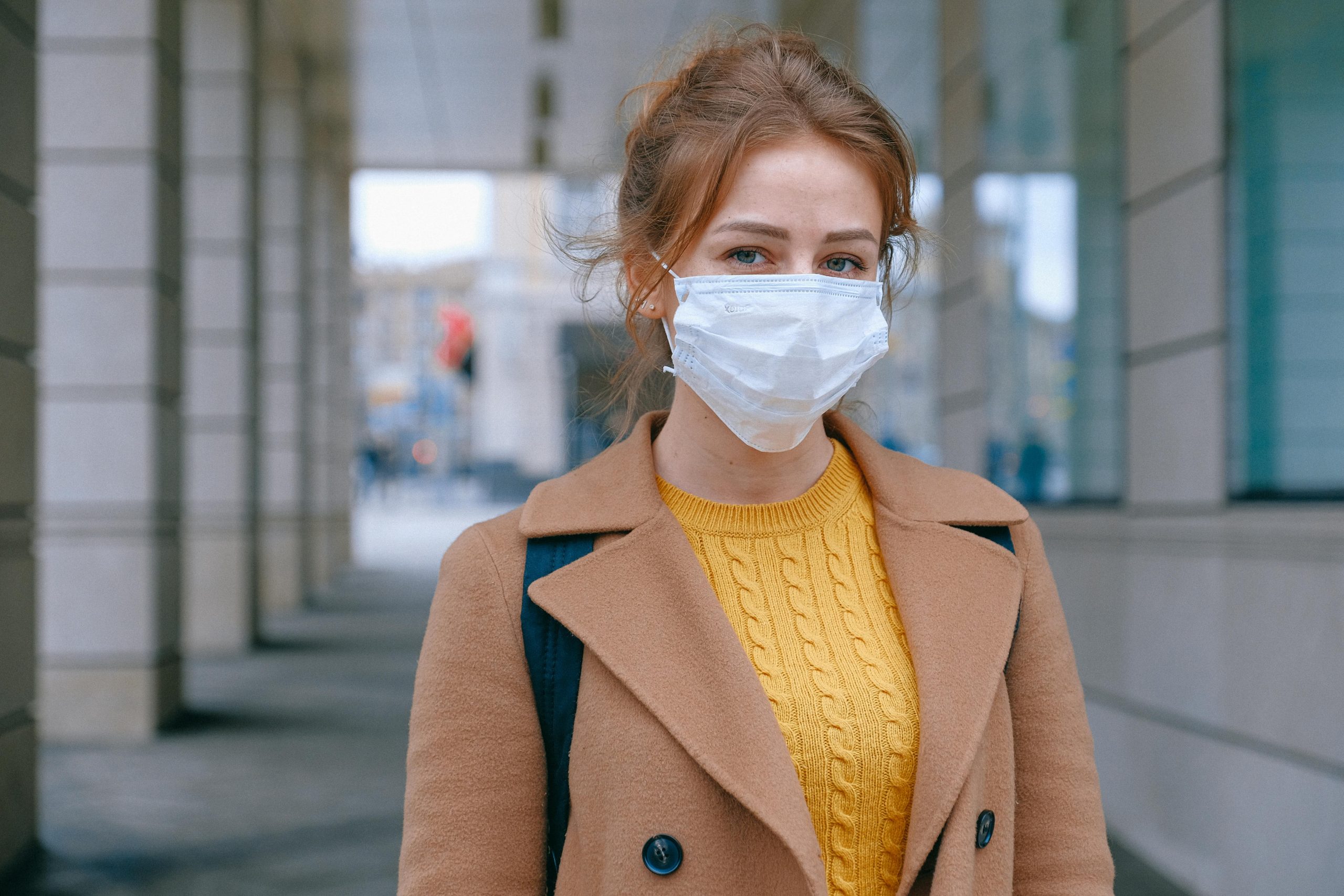 Woman in a medical mask standing outside a hospital