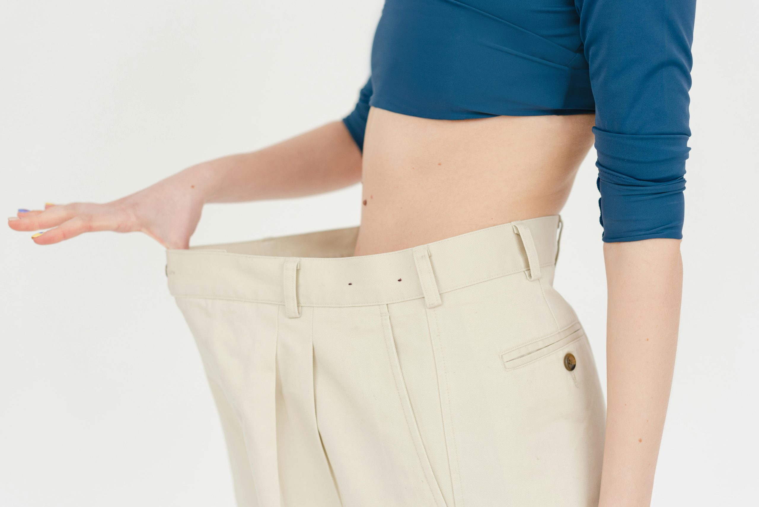 Woman holding pants stretched out that are too big from weight loss