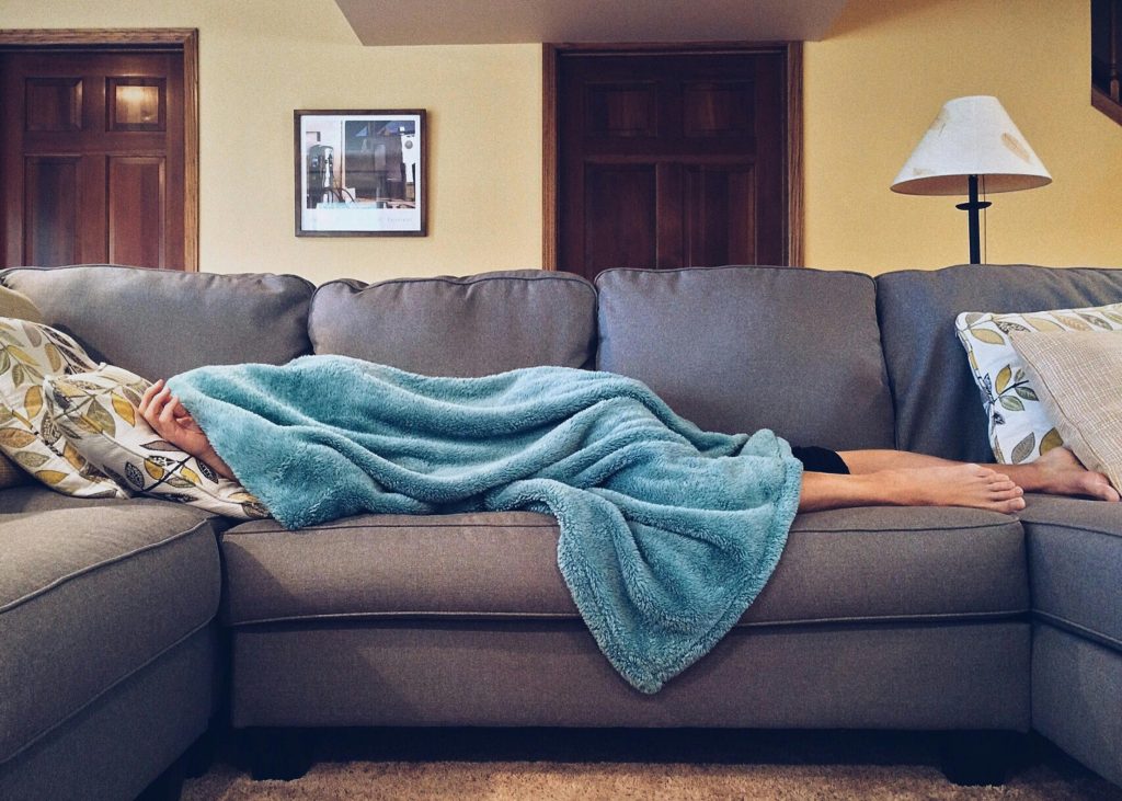 Person sleeping on the couch under a blanket