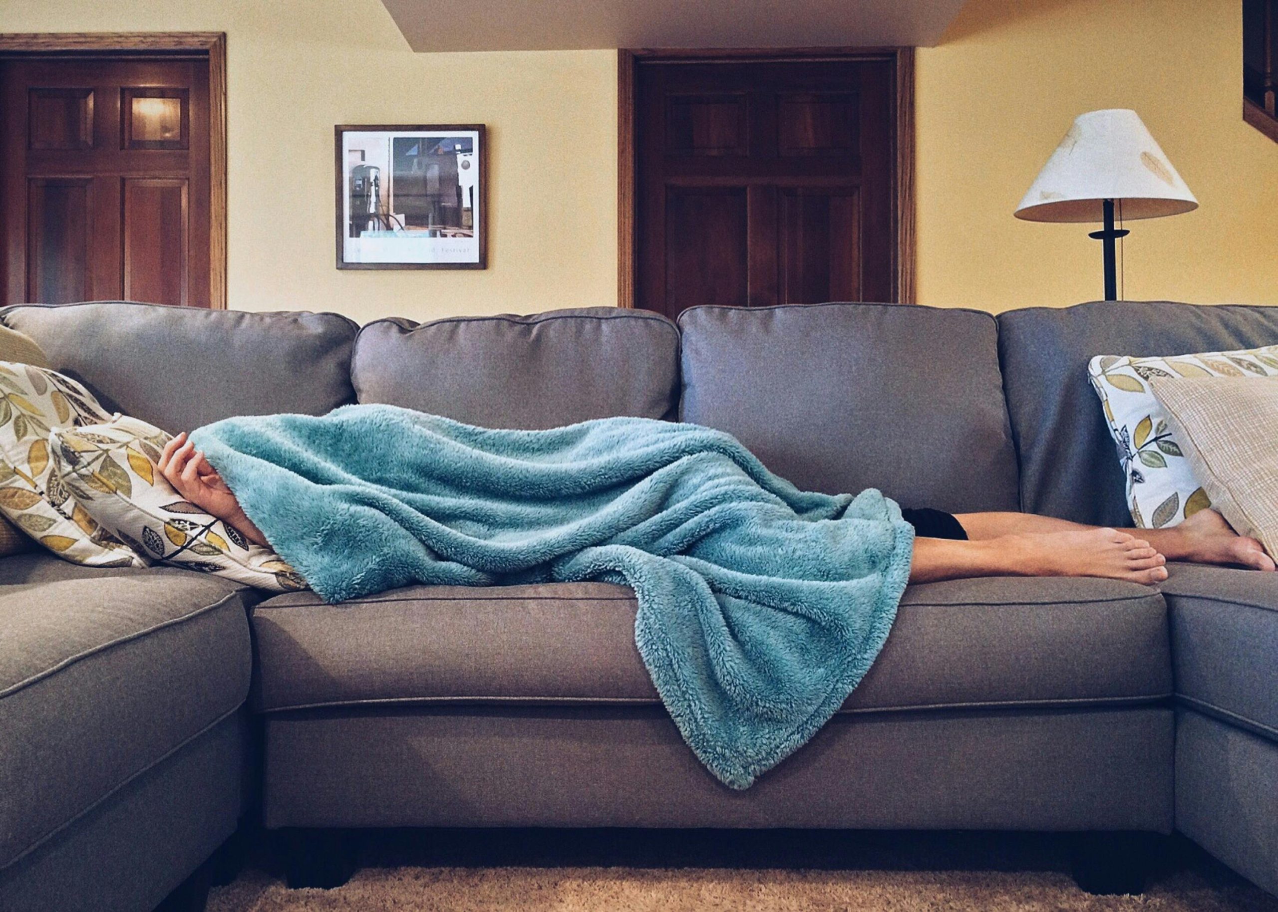 Person sleeping on the couch under a blanket